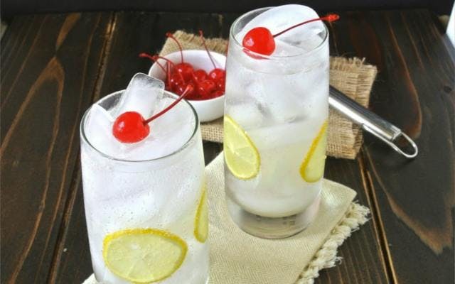 tom collins gin cocktail with lemon and cherries garnish