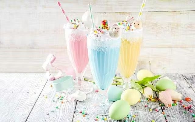 Three colourful milkshakes with a creamy topping and sprinkles