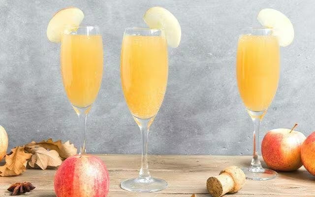 Three apple cocktails in champagne flutes and apple slice garnish
