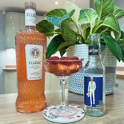 bottle of fluere 0% spirit and a raspberry cocktail in a coupe glass