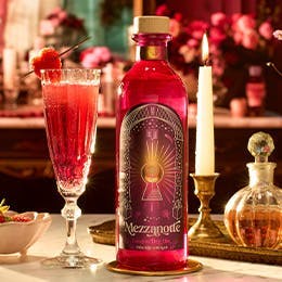 Craft Gin Club's February 2024 Gin of the Month, Gin Mezzanotte with a red, fizzy cocktail in a champagne flute