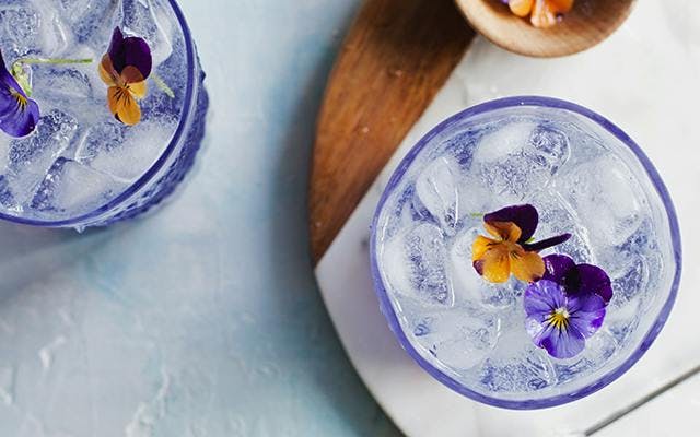 Purple fleur collins cocktail with edible flowers