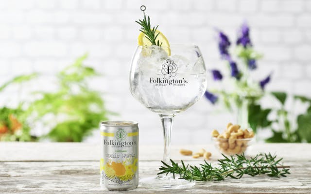 Folkington's tonic water can and gin and tonic in copa glass over ice with lemon and rosemary to garnish