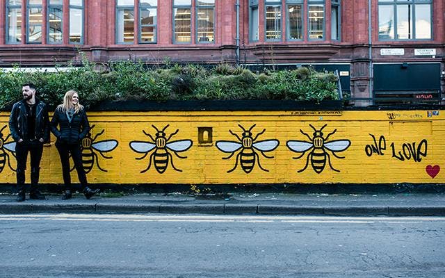 Seb Heeley and Jen Wiggins of Manchester Gin against bumble bee graffiti