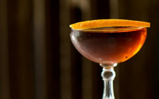 Martinez Red Orange cocktail in martini glass with orange twist garnish