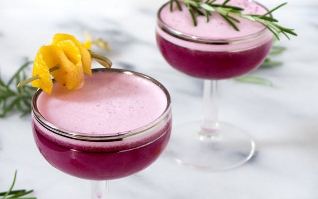 Blueberry purple gin sours with orange peel garnish