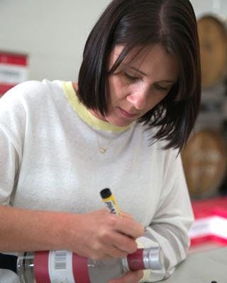 Rachel Hall labeling Lighthouse gin bottles at the distillery