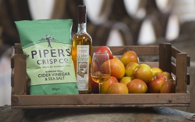 Pipers Seal salt and cider vinegar crisps with a glass of cider and apples